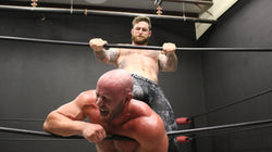 Viking is pressing Brute against the ropes with his foot on thunders arena 