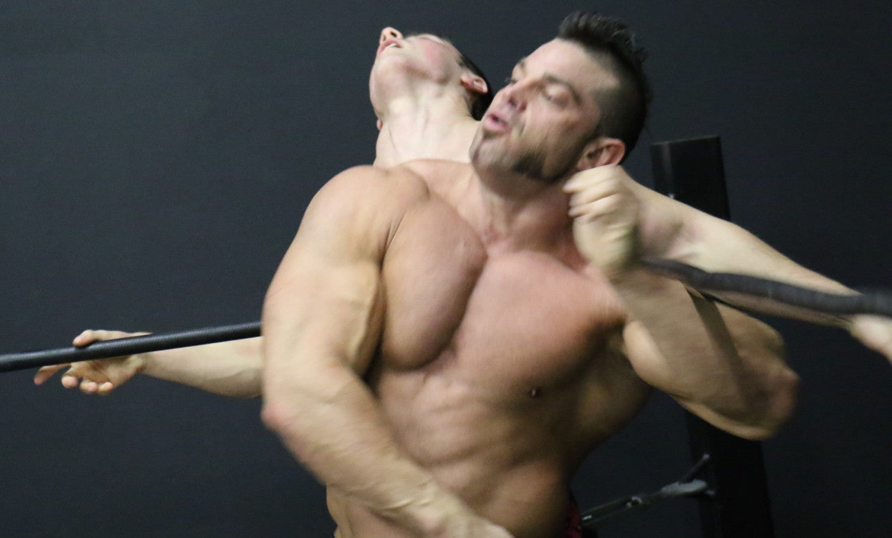 Bolt headlocks Brian Cage from behind pecs arms bicep