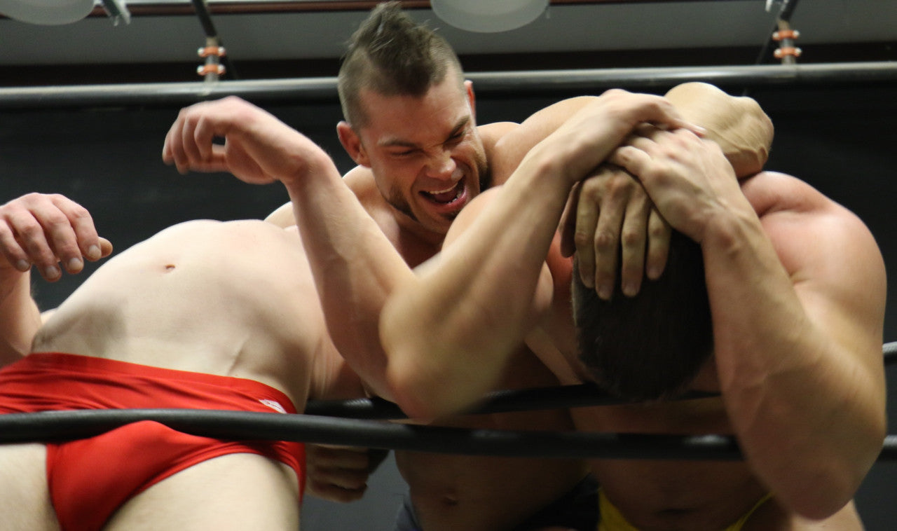 Brian Cage chokes Joey King on the ropes and has Travis in a headlock