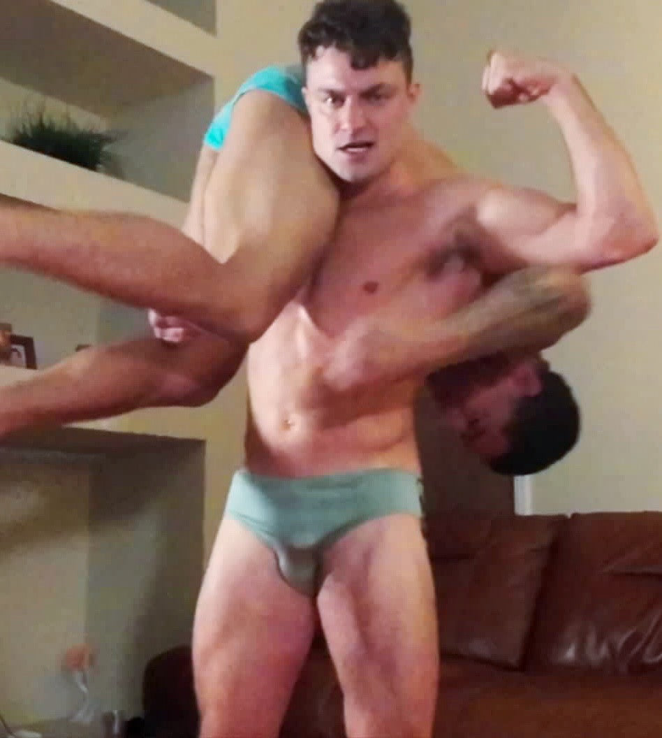 Muscle hunk flexes with opponent over shoulder