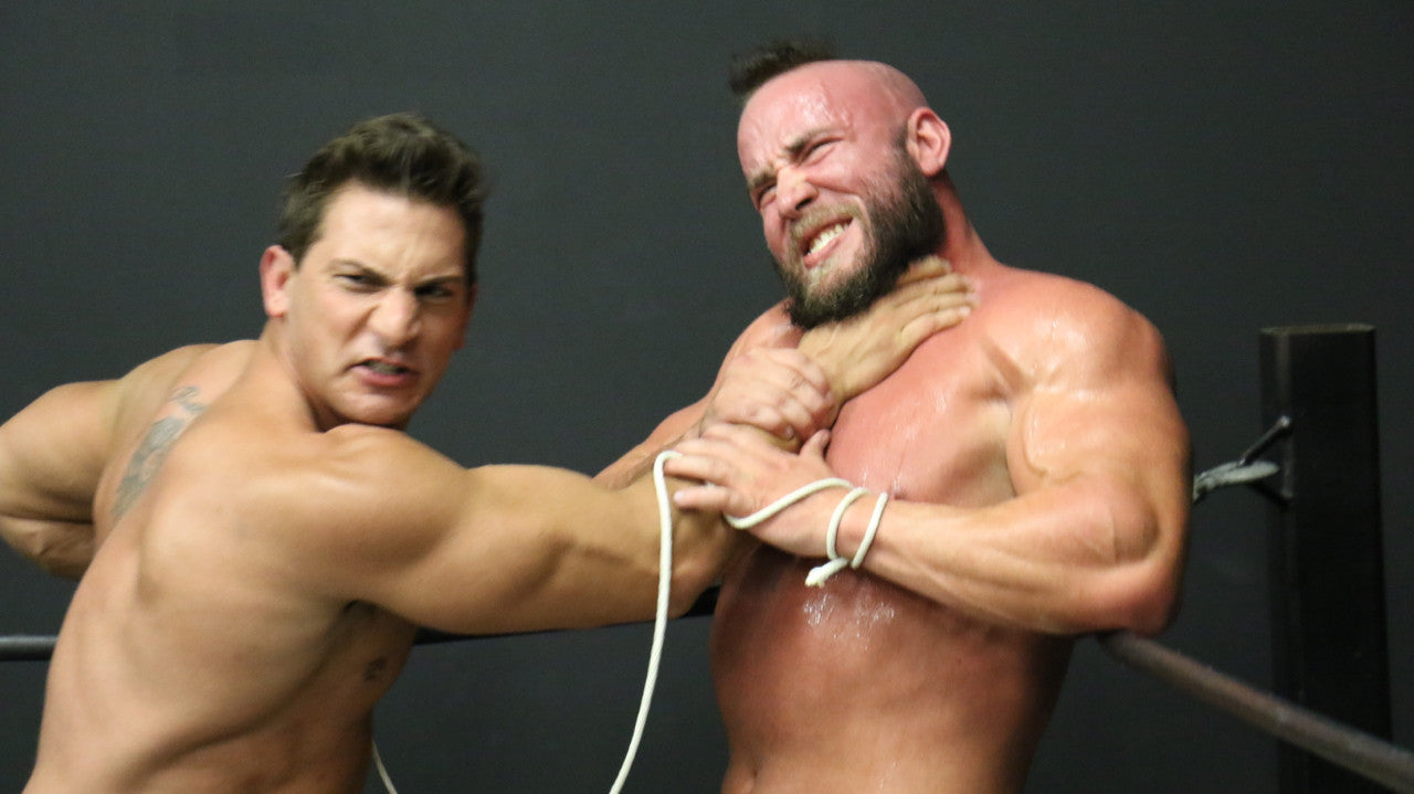 PeeWee chokes Brute in the corner of the ring on the ropes