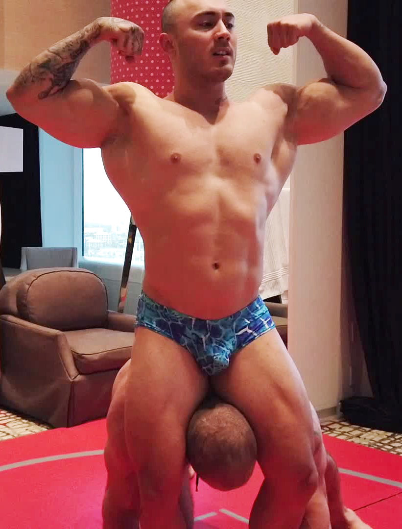 Caesar double bicep flexing while head scissoring Davin